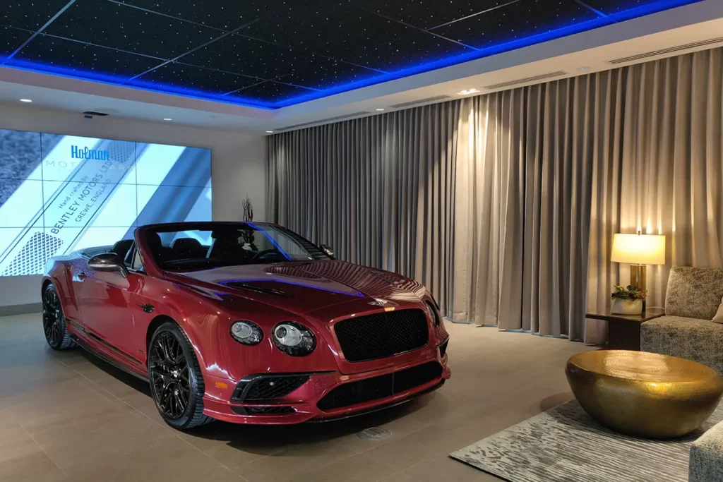 red car in a showroom with star ceiling panels and blue perimeter lighting curtains in the backgroud